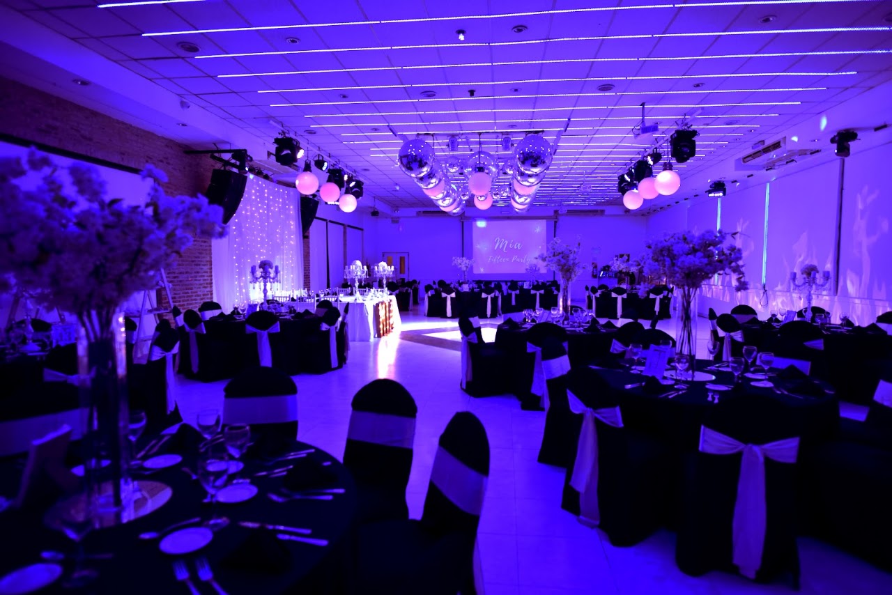 Salón interior Petra Eventos ambientado con luces violetas, bolas de espejos y banquetes de gala